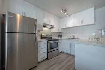 a white kitchen with stainless steel appliances and white cabinets at Napa Green Apartments LLC, California, 94559